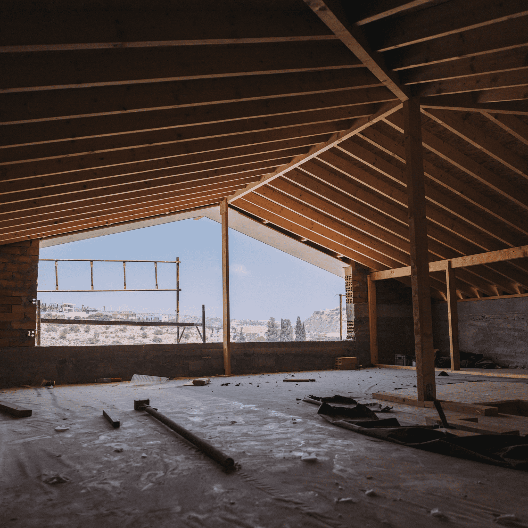 Modern home interior under construction with exposed wooden beams and scenic view outside.